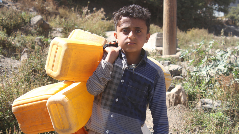 طفل يمني يحمل جراكن المياه لملئها.